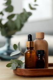 Aromatherapy. Bottles of essential oil and eucalyptus leaves on wooden table
