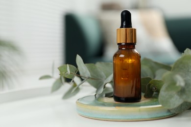 Photo of Aromatherapy. Bottle of essential oil and eucalyptus leaves on table