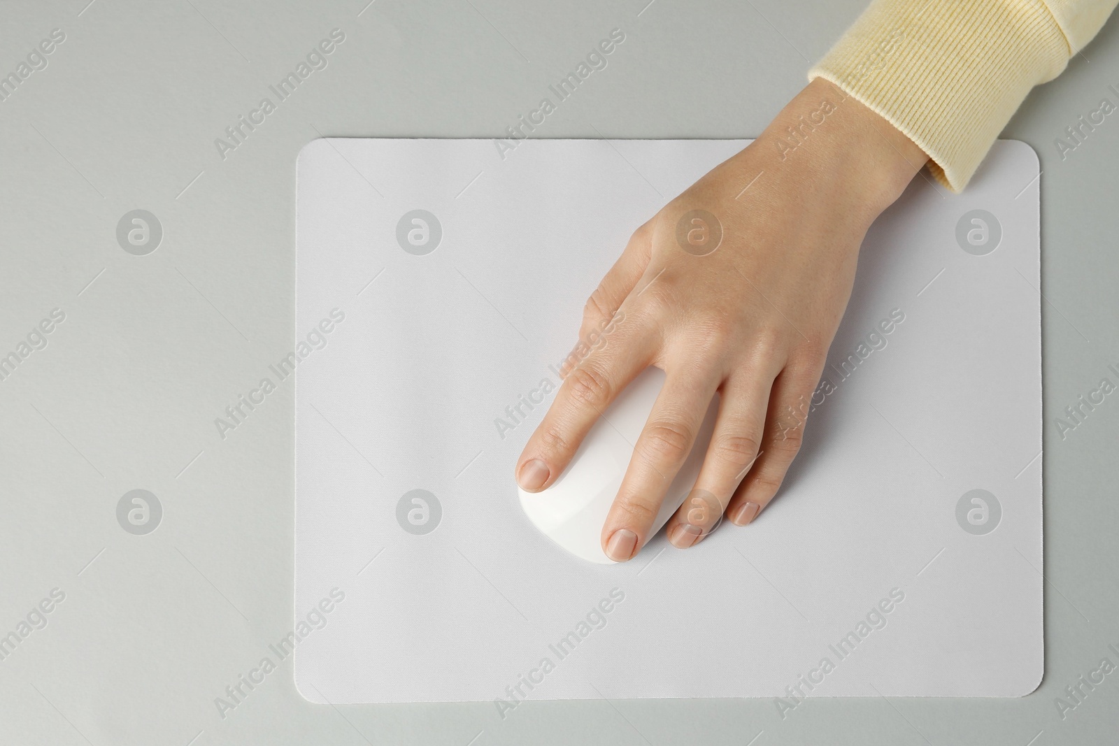 Photo of Woman using modern wireless computer mouse on grey background, top view