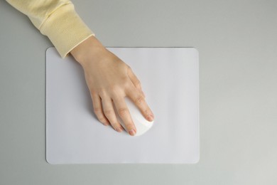 Photo of Woman using modern wireless computer mouse on grey background, top view
