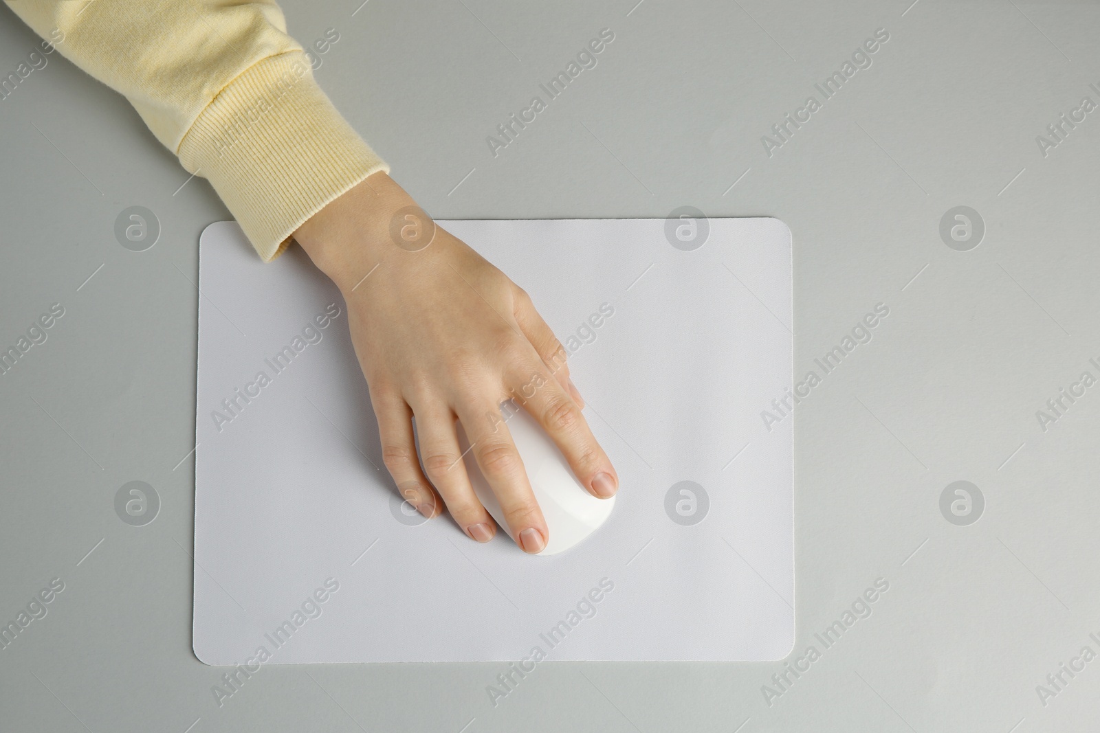 Photo of Woman using modern wireless computer mouse on grey background, top view