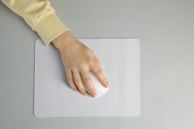 Woman using modern wireless computer mouse on grey background, top view