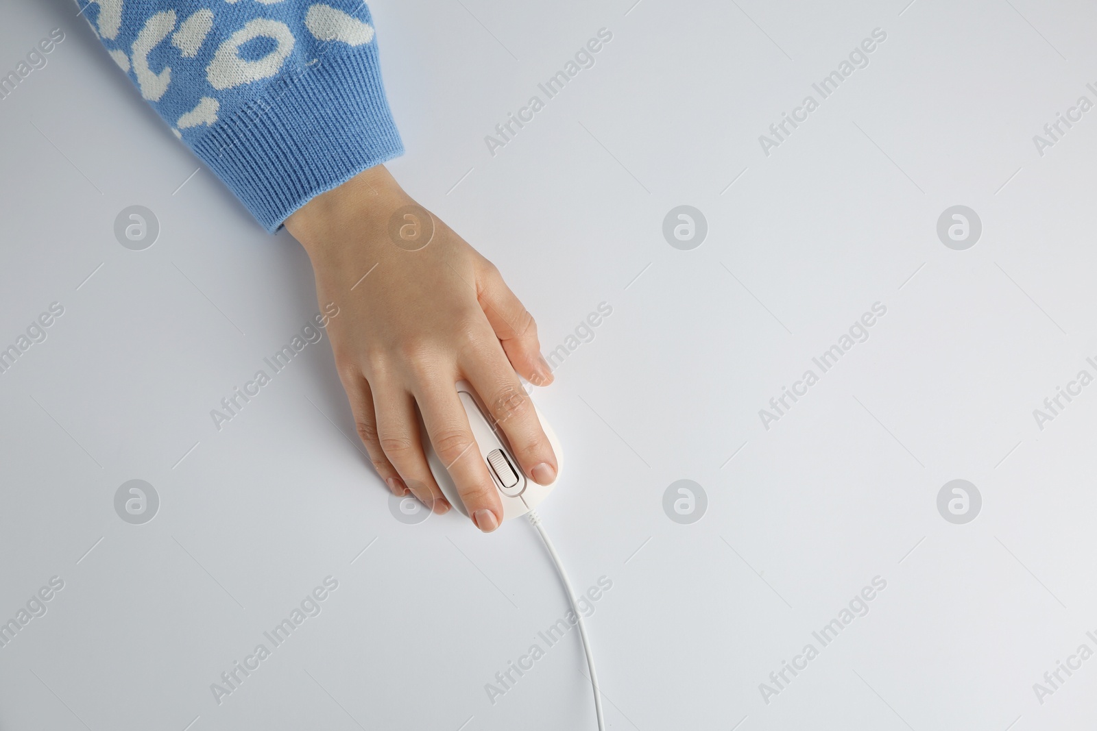 Photo of Woman using modern wired computer mouse on light background, top view. Space for text