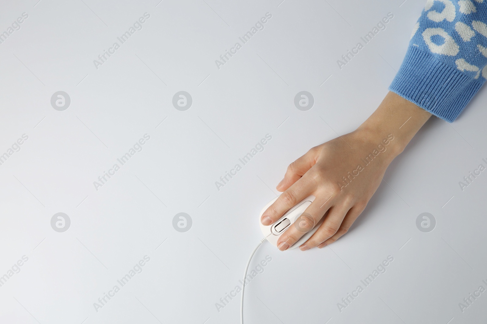 Photo of Woman using modern wired computer mouse on light background, top view. Space for text