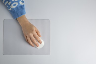 Photo of Woman using modern wireless computer mouse on light background, top view. Space for text