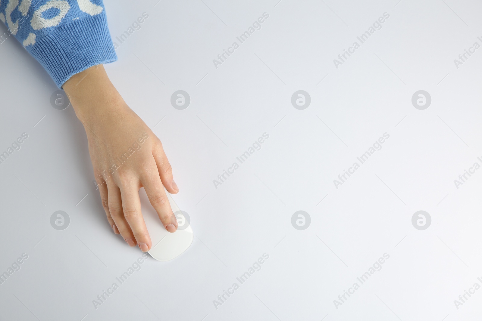 Photo of Woman using modern wireless computer mouse on light background, top view. Space for text