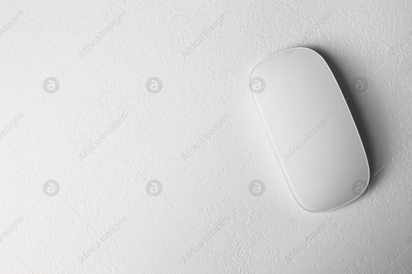 Photo of One wireless mouse on light textured table, top view. Space for text