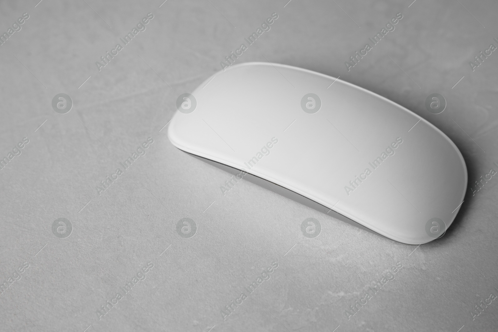 Photo of One wireless mouse on light textured table, closeup. Space for text