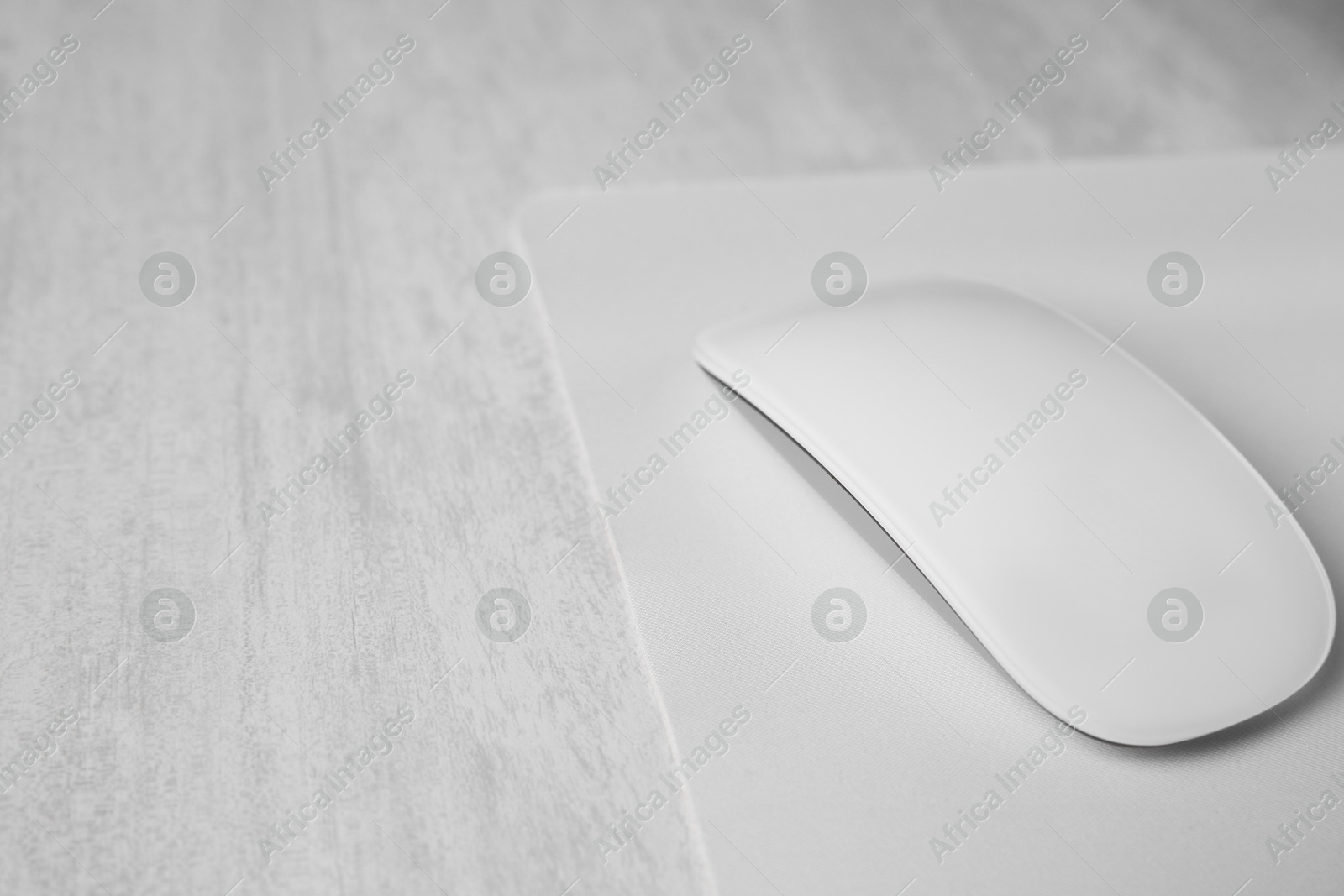 Photo of One wireless mouse with mousepad on grey wooden table, closeup. Space for text