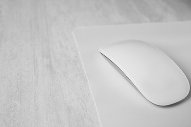 Photo of One wireless mouse with mousepad on grey wooden table, closeup. Space for text