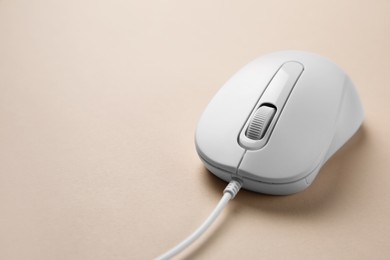 One wired mouse on beige background, closeup. Space for text