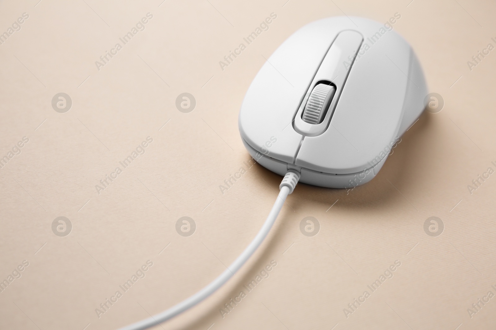 Photo of One wired mouse on beige background, closeup