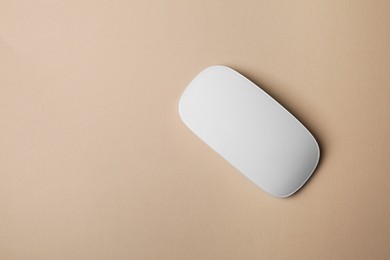 One wireless mouse on beige background, top view. Space for text
