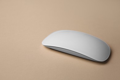 Photo of One wireless mouse on beige background, closeup. Space for text