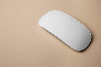 One wireless mouse on beige background, closeup. Space for text