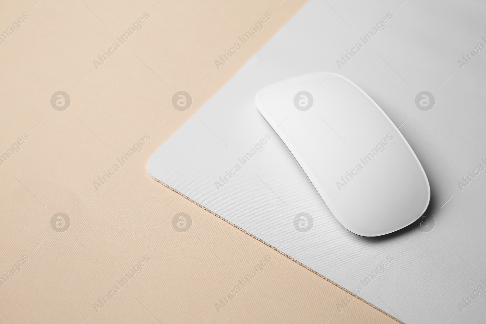 Photo of One wireless mouse with mousepad on beige background, closeup. Space for text