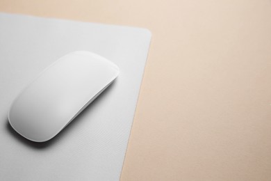 One wireless mouse with mousepad on beige background, closeup. Space for text