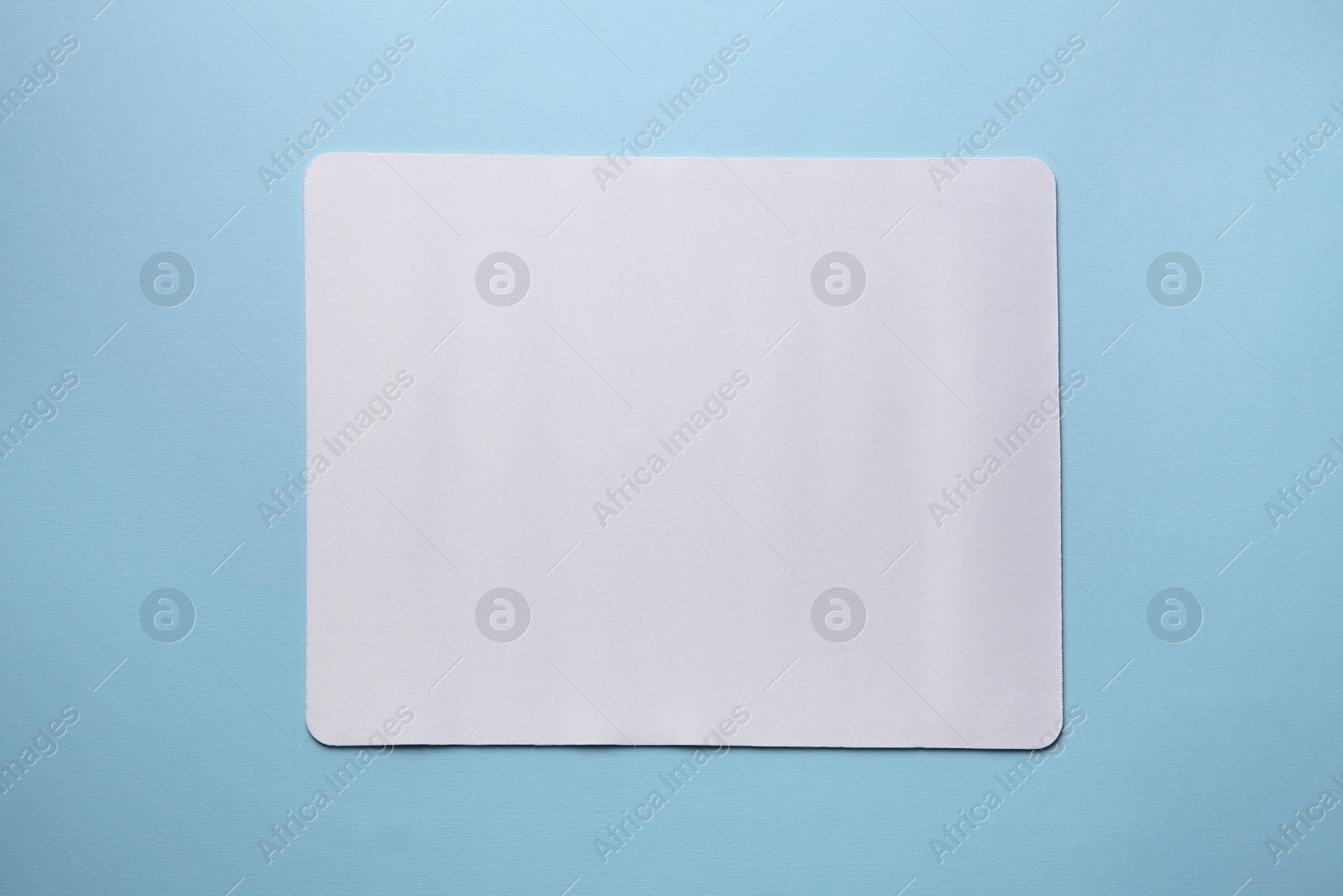 Photo of One mouse pad on light blue background, top view. Space for text