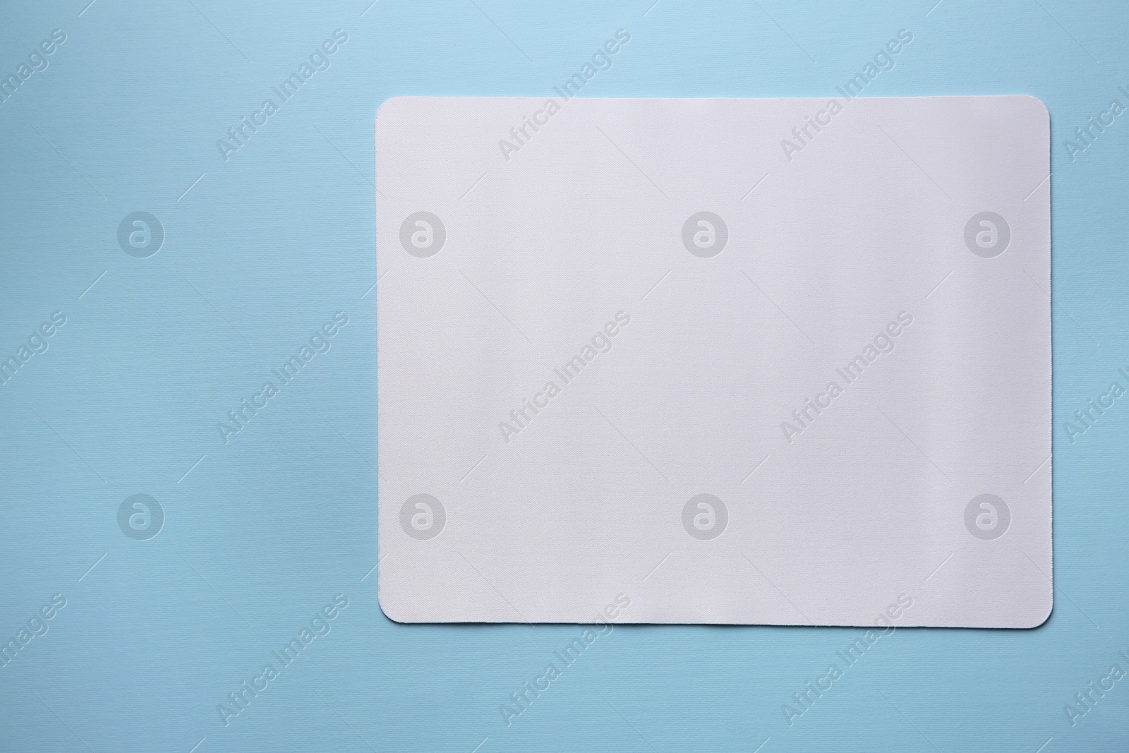 Photo of One mouse pad on light blue background, top view. Space for text
