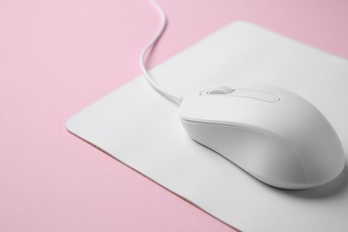 Photo of One wired mouse with mousepad on pink background, closeup