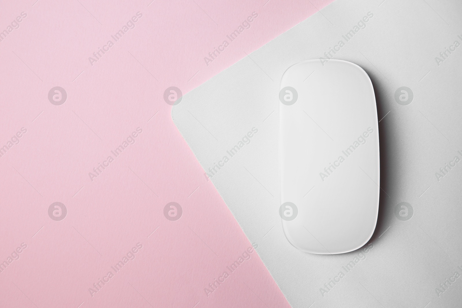 Photo of One wireless mouse with mousepad on pink background, top view. Space for text