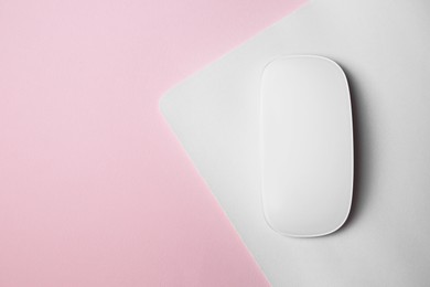 Photo of One wireless mouse with mousepad on pink background, top view. Space for text