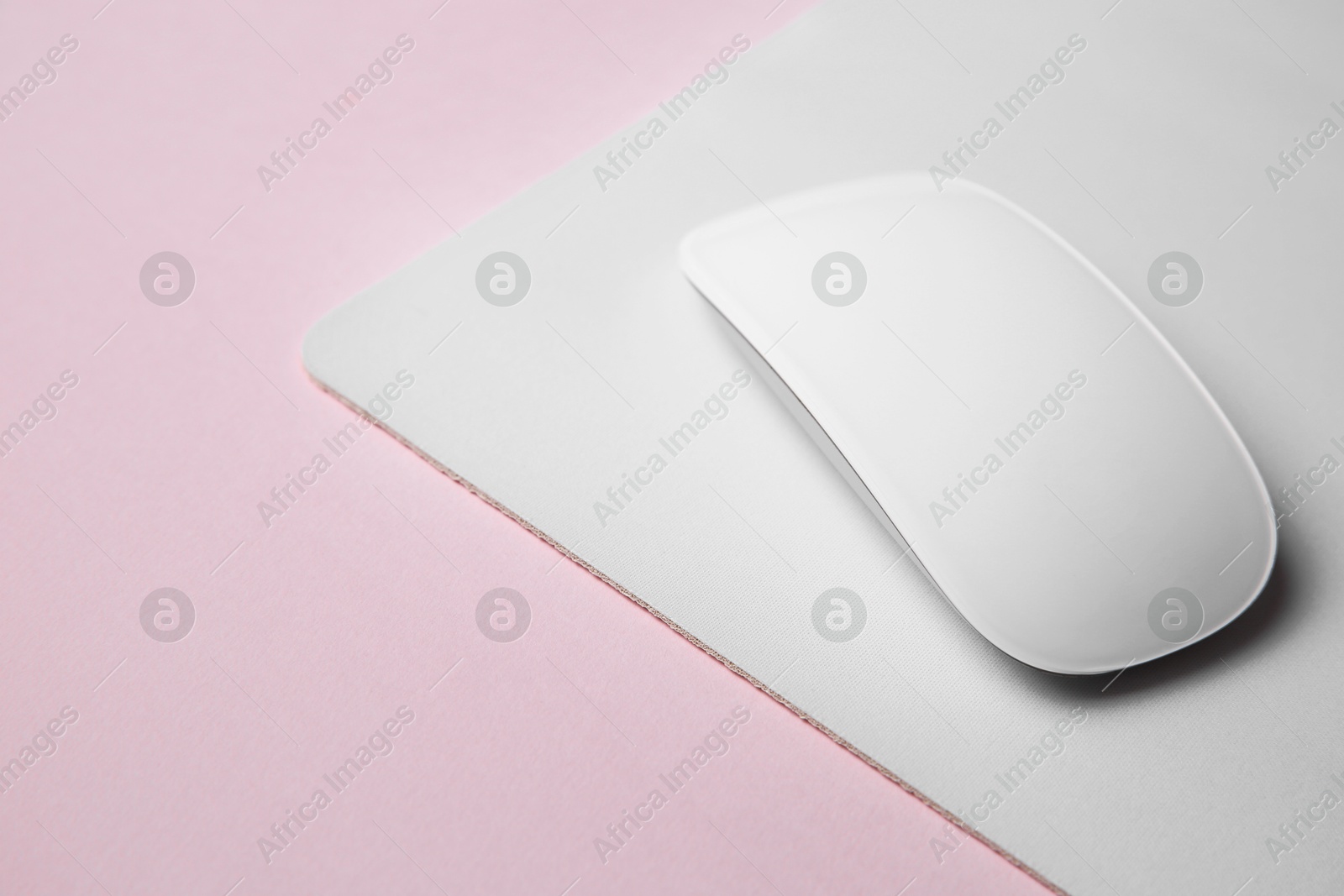 Photo of One wireless mouse with mousepad on pink background, closeup. Space for text