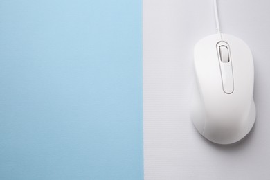 Photo of Wired mouse with mousepad on light blue background, top view. Space for text