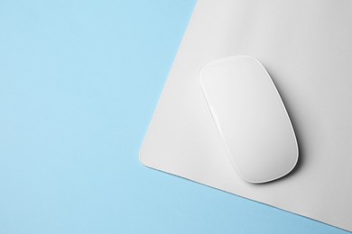 One wireless mouse with mousepad on light blue background, top view. Space for text