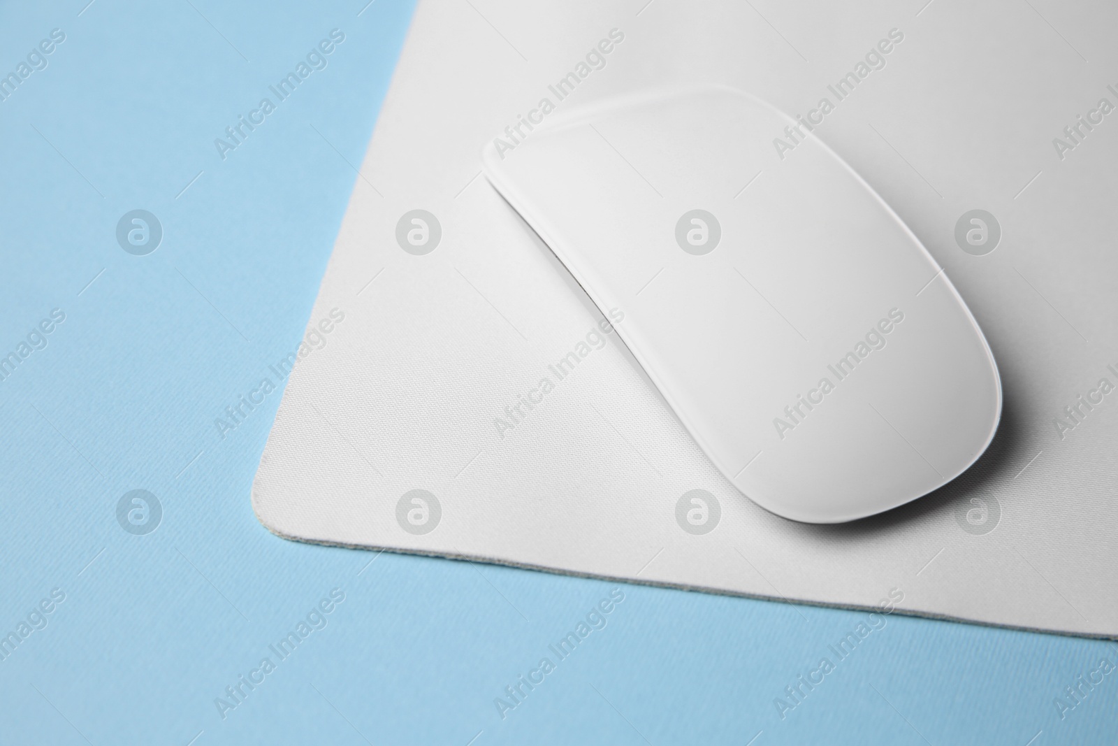 Photo of One wireless mouse with mousepad on light blue background