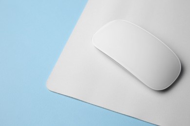 Photo of One wireless mouse with mousepad on light blue background. Space for text