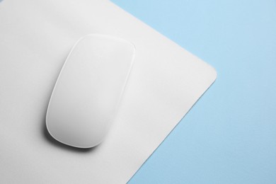 One wireless mouse with mousepad on light blue background, above view. Space for text