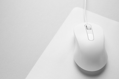 Wired mouse with mousepad on grey background, closeup. Space for text