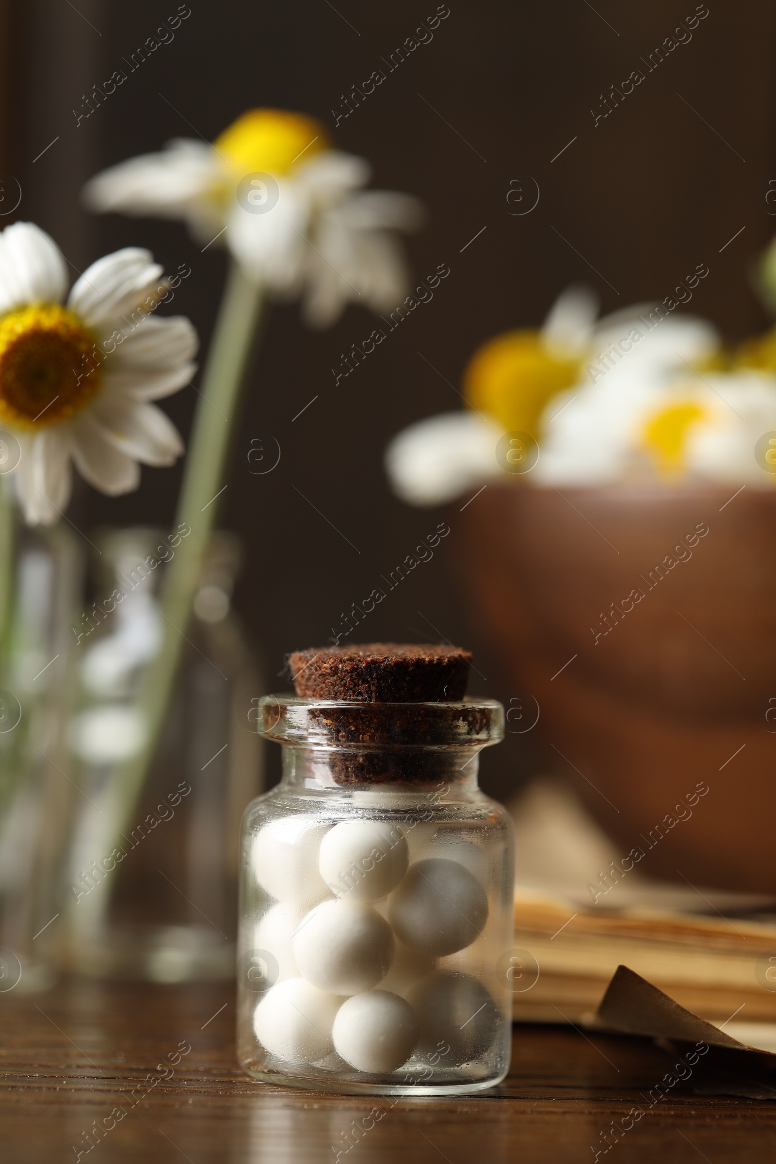 Photo of Homeopathy. Pills in glass bottle on wooden table, closeup