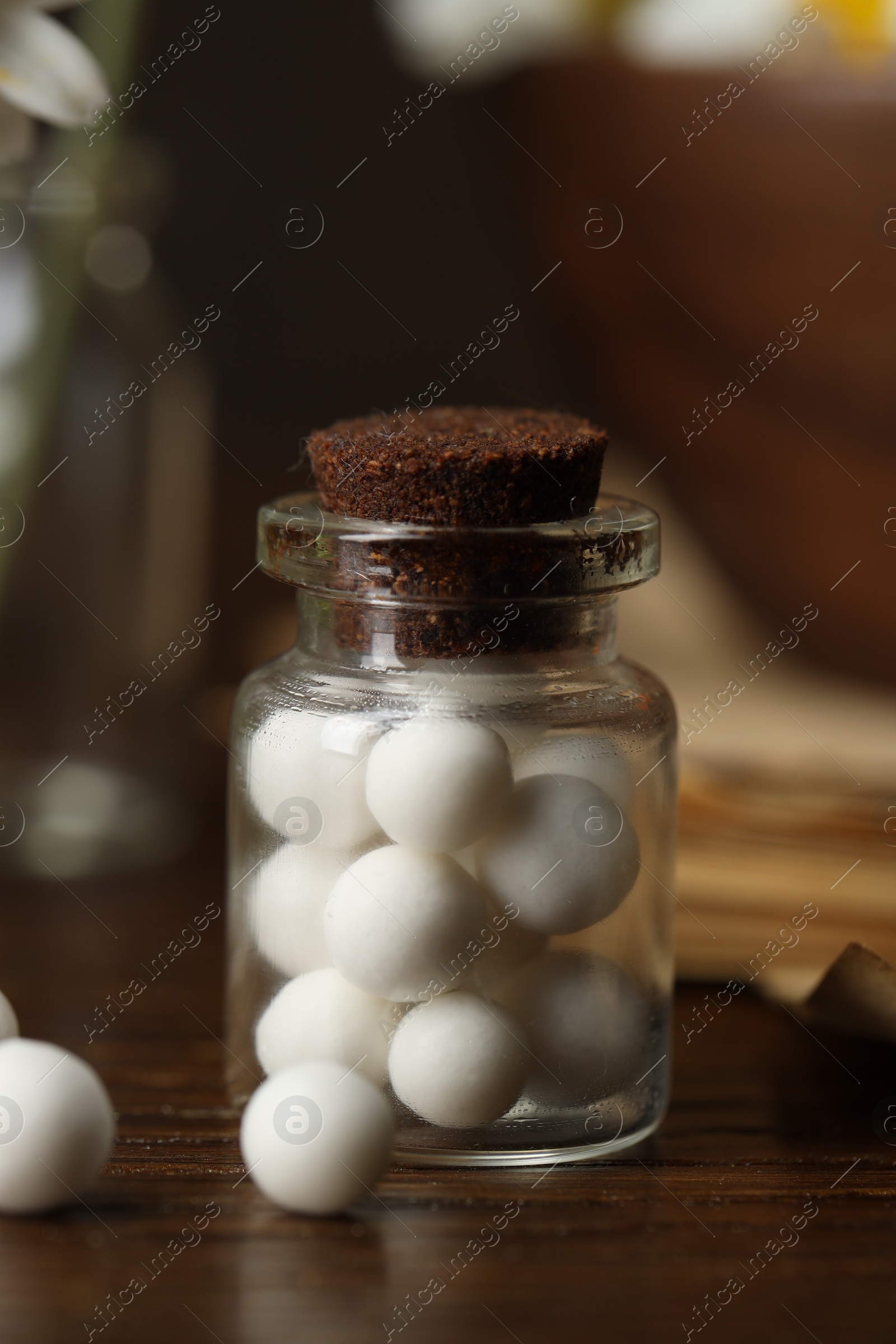 Photo of Homeopathy. Pills in glass bottle on wooden table, closeup