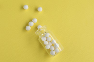 Photo of Bottle with homeopathic remedy on yellow background, top view