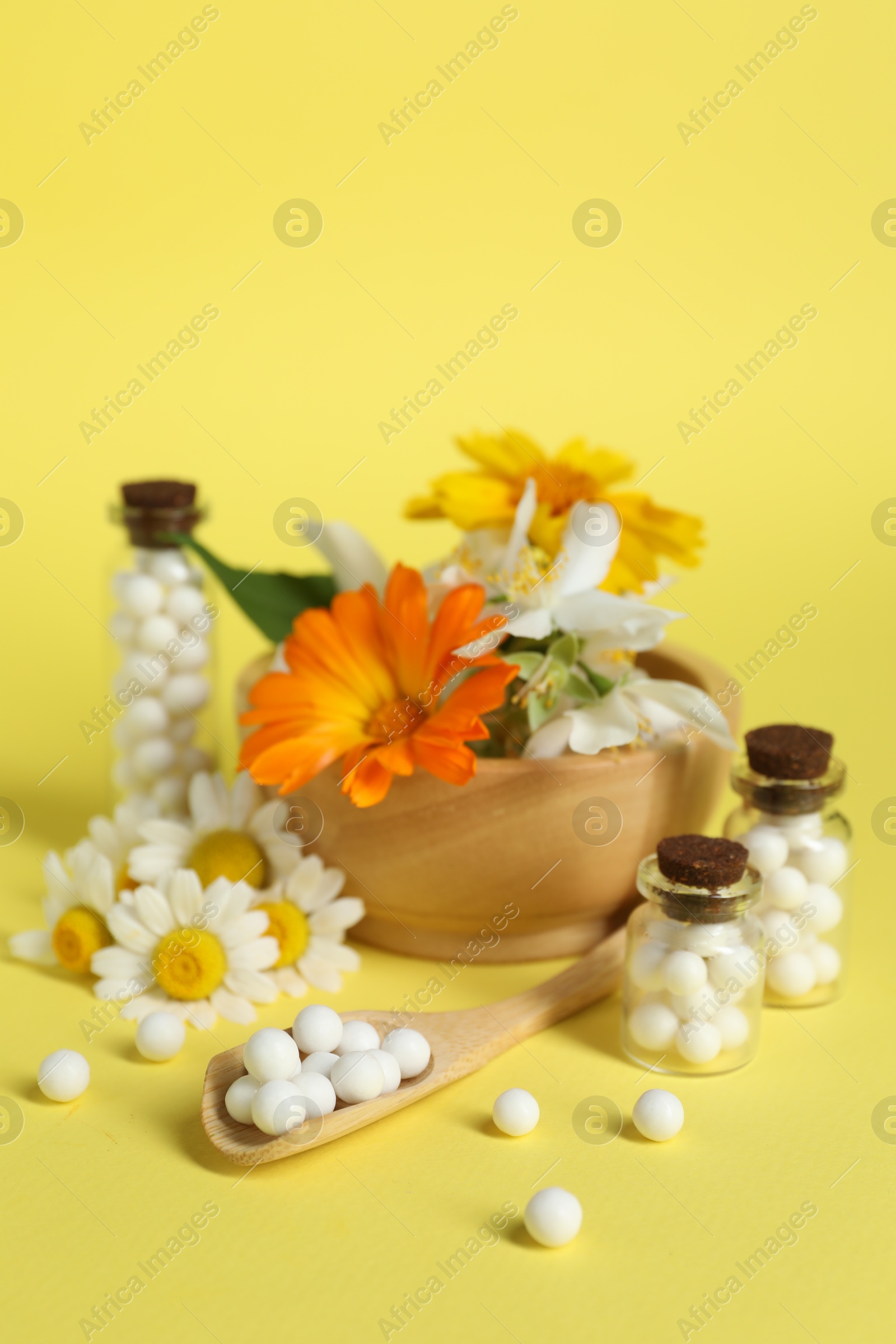 Photo of Homeopathic remedy and flowers on yellow background