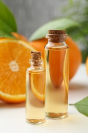 Essential oils in bottles and oranges on white table