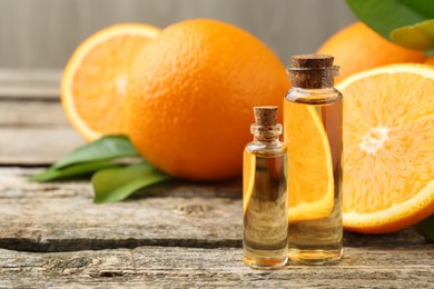 Essential oils in bottles, oranges and green leaves on wooden table