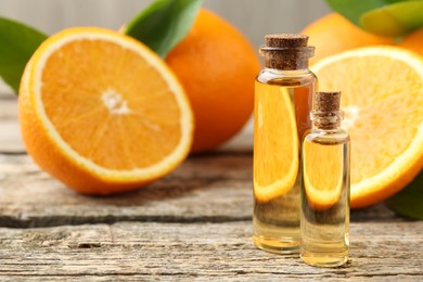 Photo of Essential oils in bottles and oranges on wooden table