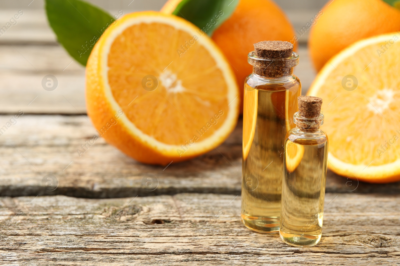 Photo of Essential oils in bottles and oranges on wooden table