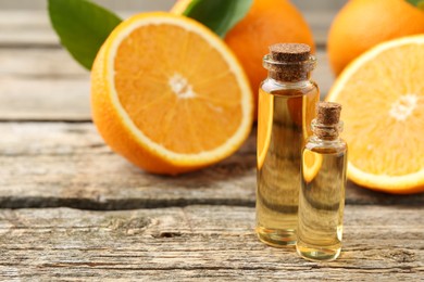 Photo of Essential oils in bottles and oranges on wooden table