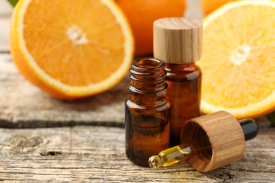 Essential oils in bottles, dropper and oranges on wooden table, closeup