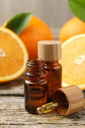 Photo of Essential oils in bottles, dropper and oranges on wooden table