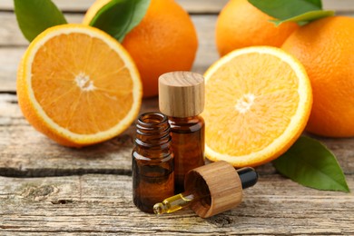 Essential oils in bottles, dropper, oranges and green leaves on wooden table