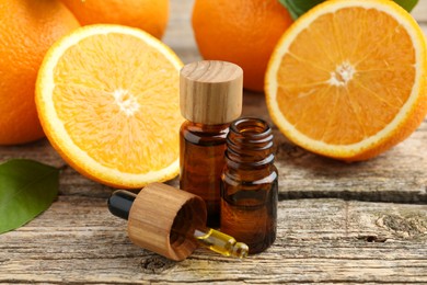 Essential oils in bottles, dropper, oranges and green leaf on wooden table