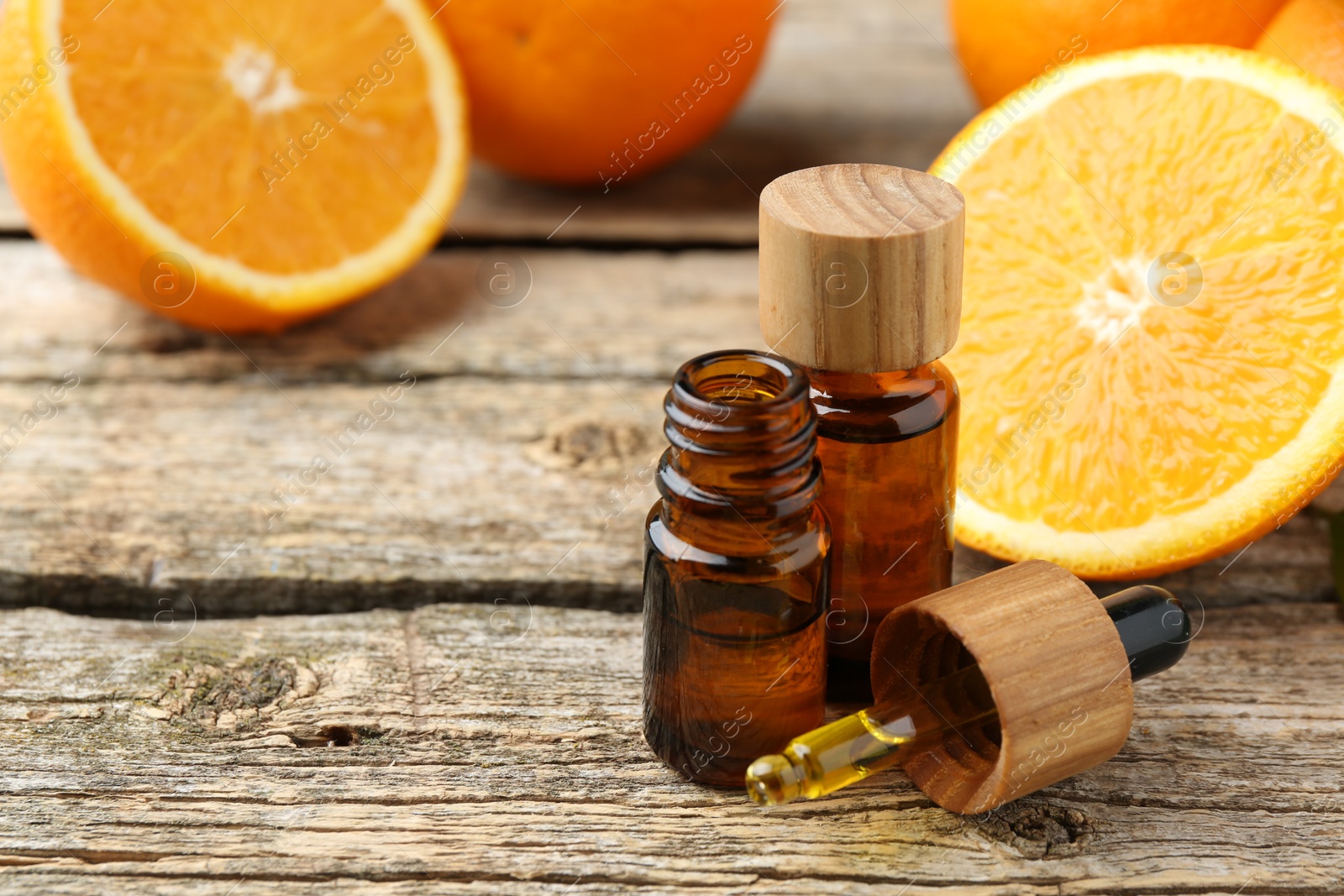 Photo of Essential oils in bottles, dropper and oranges on wooden table