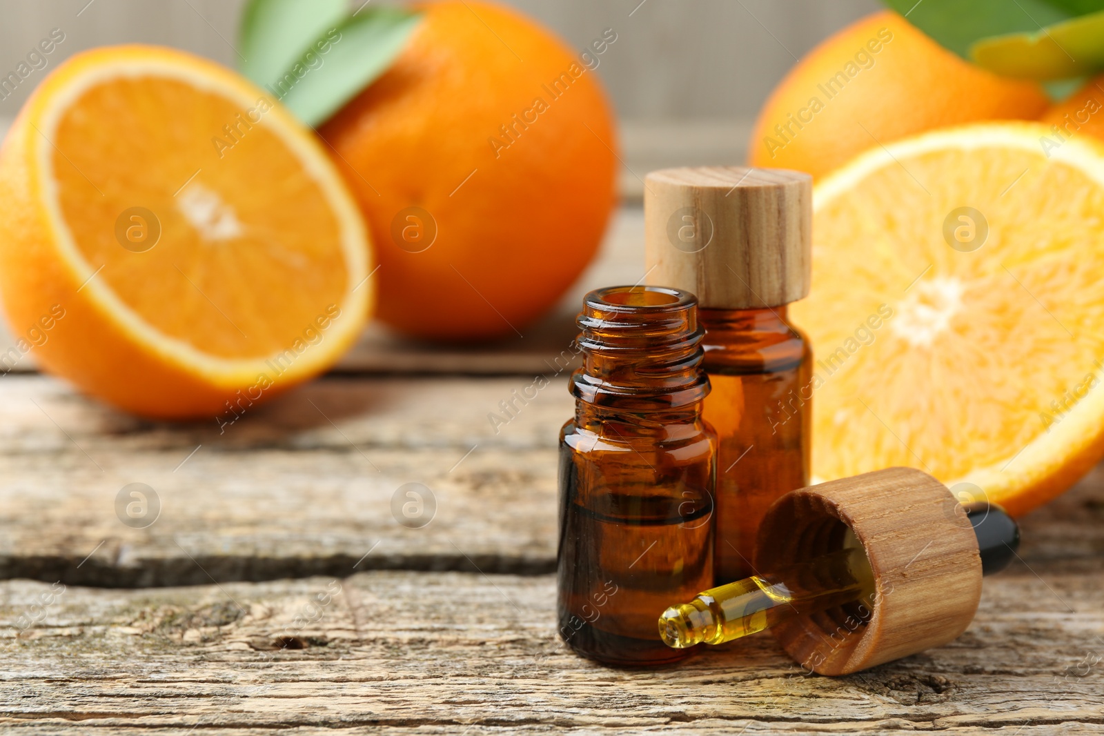 Photo of Essential oils in bottles, dropper and oranges on wooden table