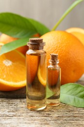 Essential oils in bottles, oranges and green leaves on wooden table