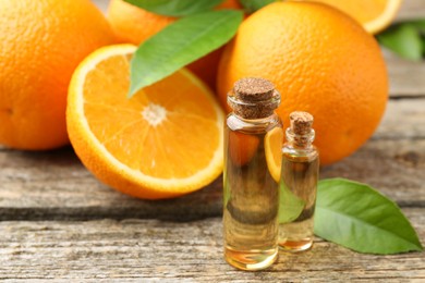 Essential oils in bottles, oranges and green leaves on wooden table